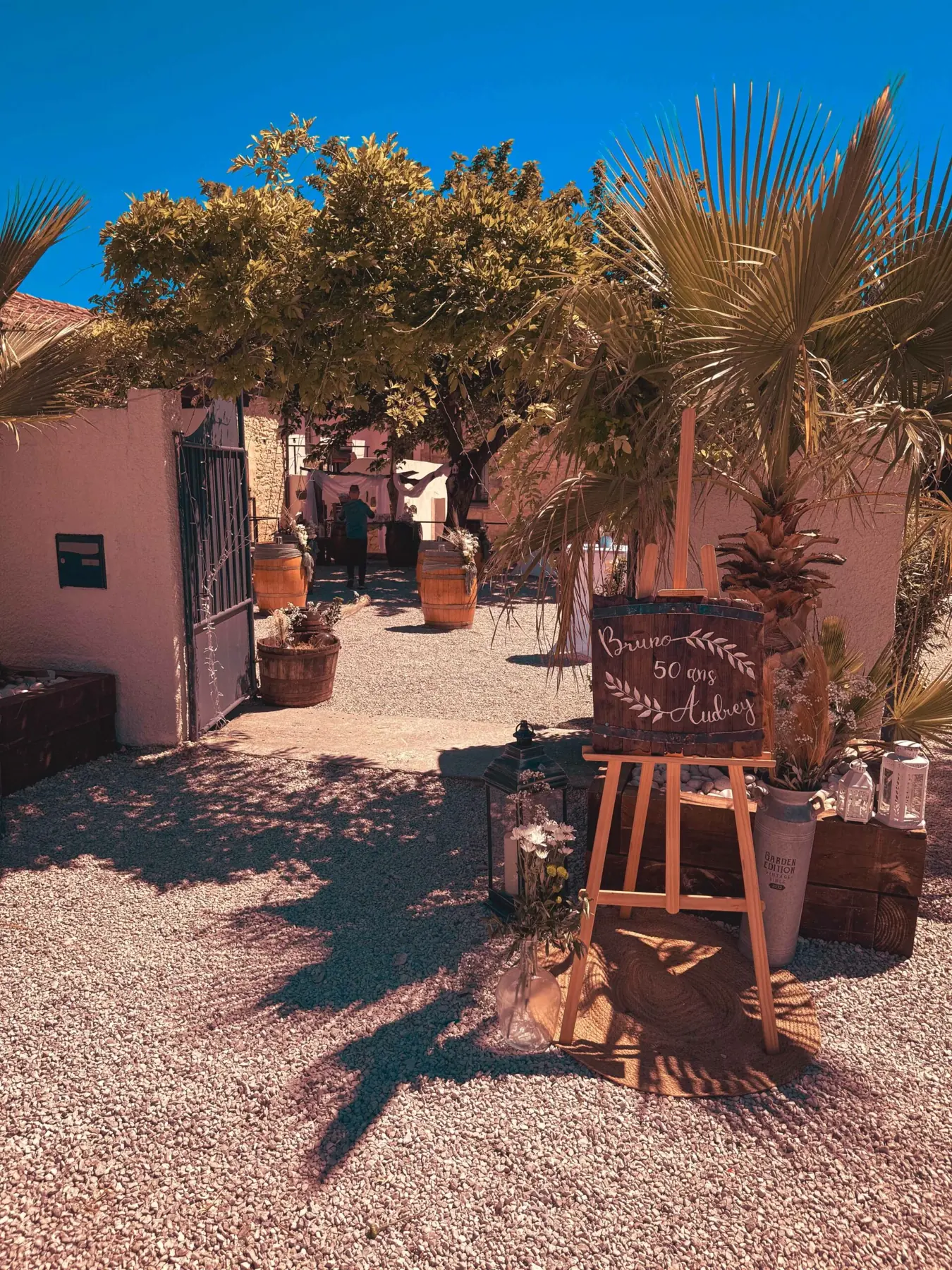 L'entrée du petit patio sous son arche, entre palmier et tonneaux